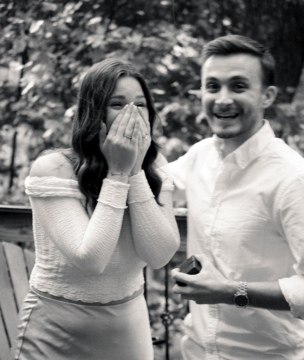 Black and white: Caroline covering her mouth as Chandler grins