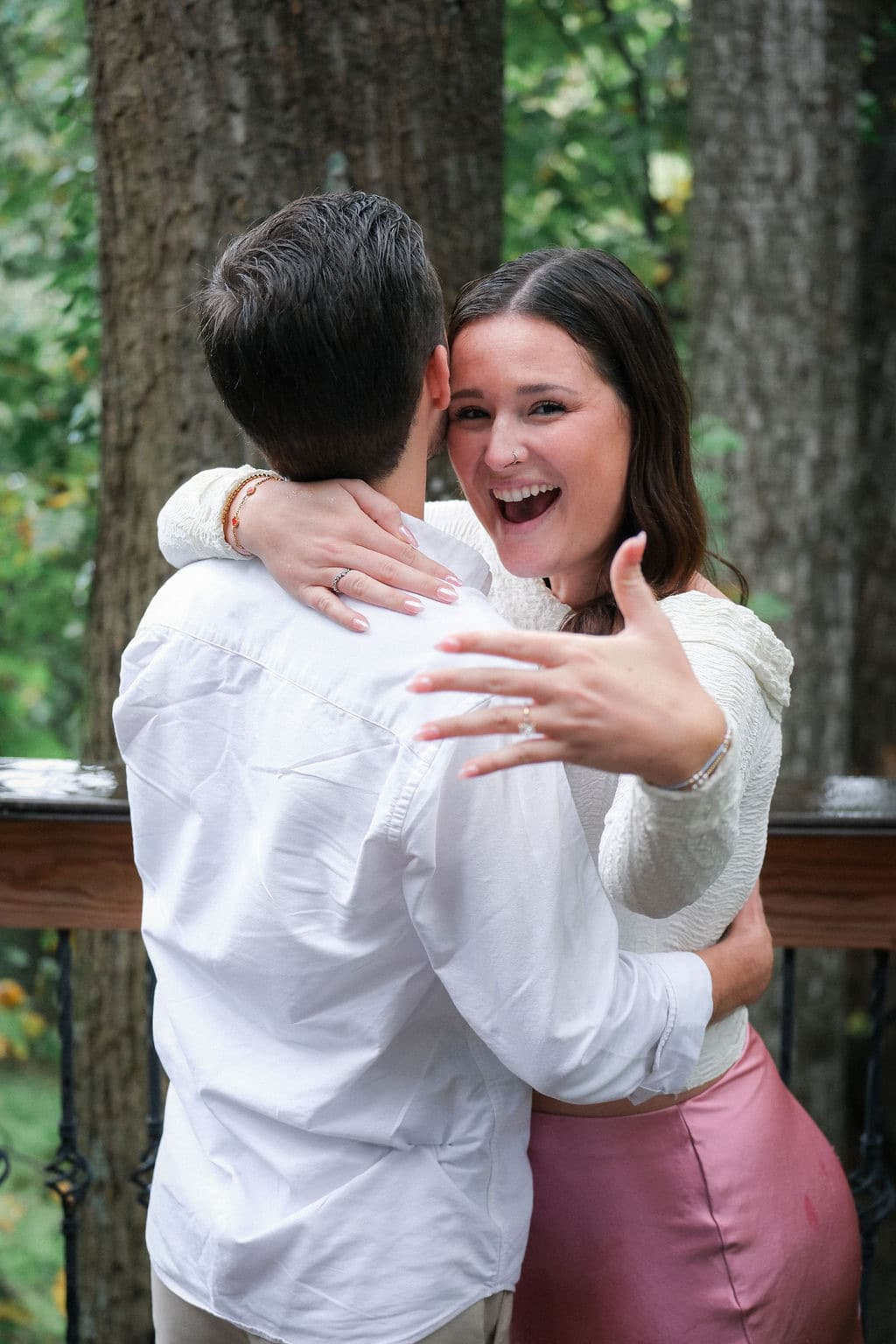 Caroline laughing over Chandler's shoulder, ring on her hand
