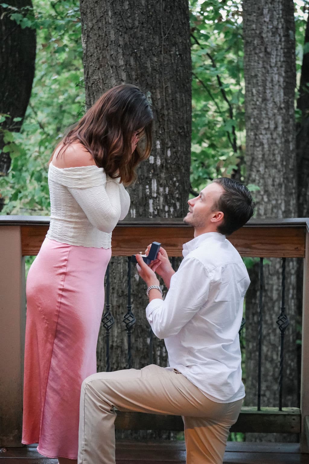 Chandler on one knee on the deck, holding out the ring