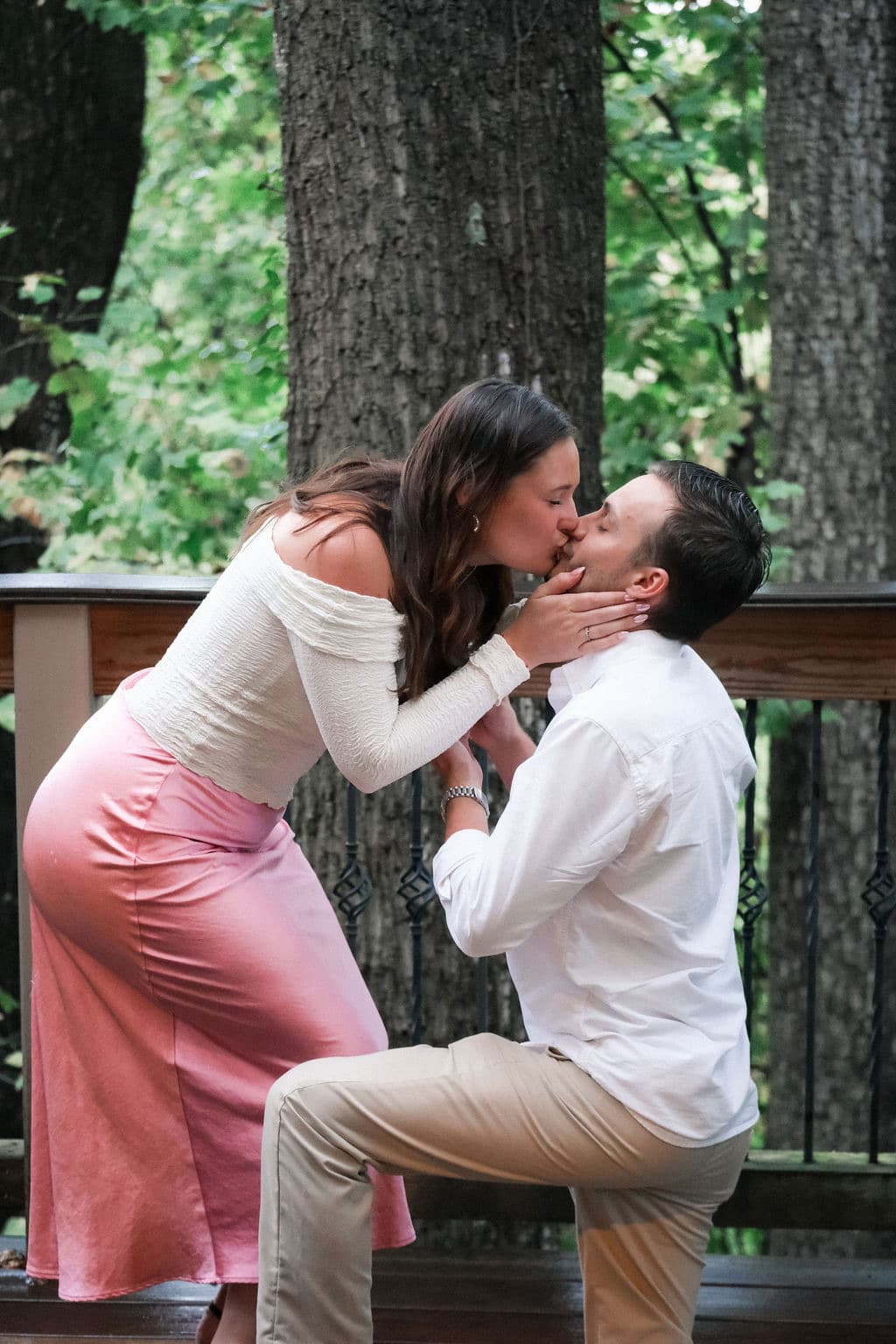 Caroline leaning down to kiss Chandler while he kneels